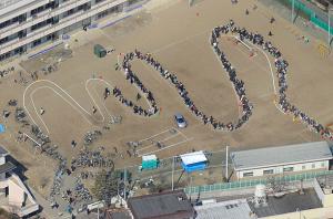 Efter tsunamin: Människor som köar för vatten vid en skola i Sendai, Japan.